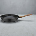 Schwarze Bratpfanne mit Antihaftbeschichtung und ergonomischem Holzgriff auf grauem Hintergrund