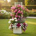 Weißer Garten-Pflanzkübel mit Rankgitter, bepflanzt mit rosa Kletterrosen, weißen Hortensien und hängenden Petunien in einem gepflegten Garten bei warmem Sonnenlicht.