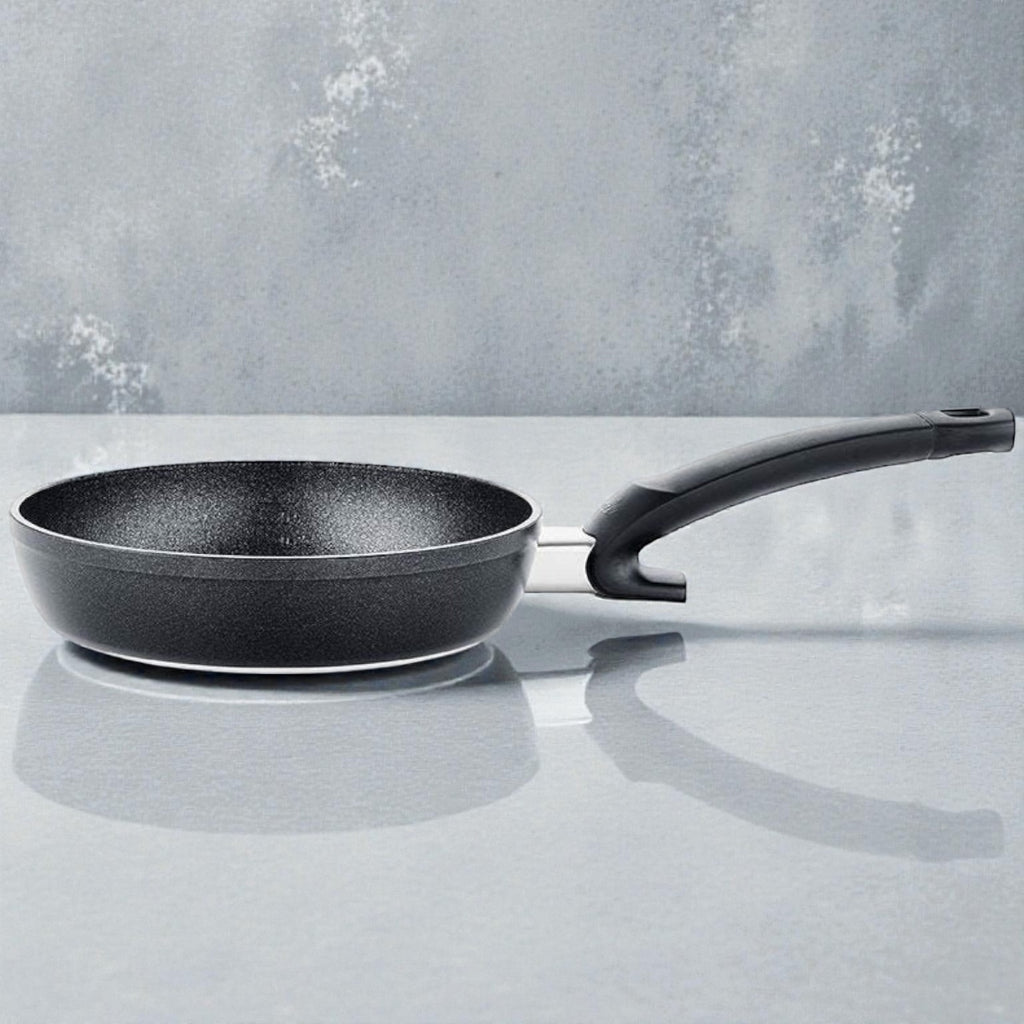 Schwarze Antihaft-Bratpfanne mit ergonomischem Griff auf heller Oberfläche