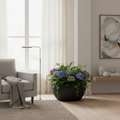 Großer schwarzer Blumentopf mit blauen Hortensien im modernen Wohnzimmer, stilvolle Innenraumdekoration mit natürlichem Licht und minimalistischer Einrichtung.