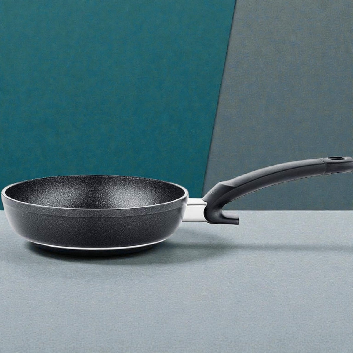 Moderne schwarze Antihaft-Bratpfanne mit ergonomischem Griff vor zweifarbigem Hintergrund
