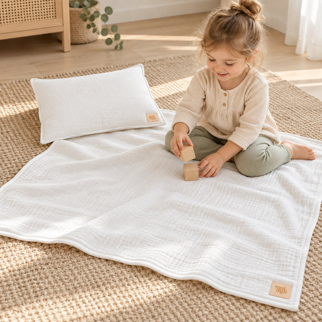 Musselin-Babydecke mit Kissen – Creme – Kind spielt neben Decke und Kissen