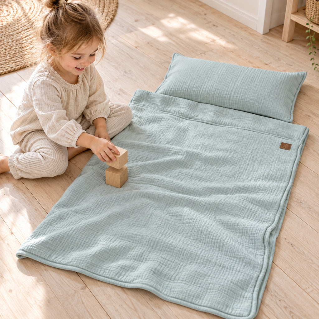 Musselin-Babydecke mit Kissen – Mint – Kind spielt neben Decke und Kissen