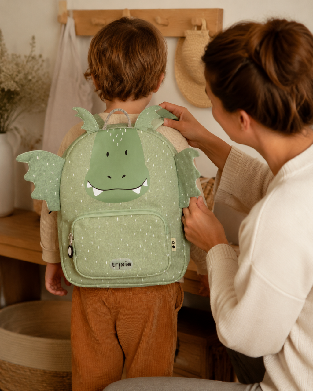 Mutter hilft Kind mit Kinderrucksack Mr. Dragon