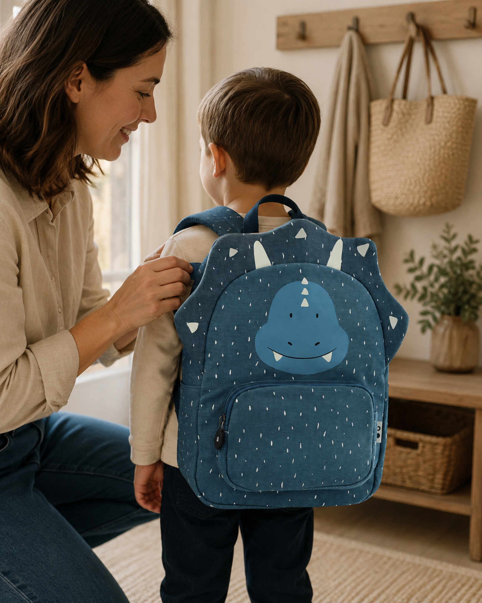 Mutter hilft Kind mit Kinderrucksack Mr. Triceratops
