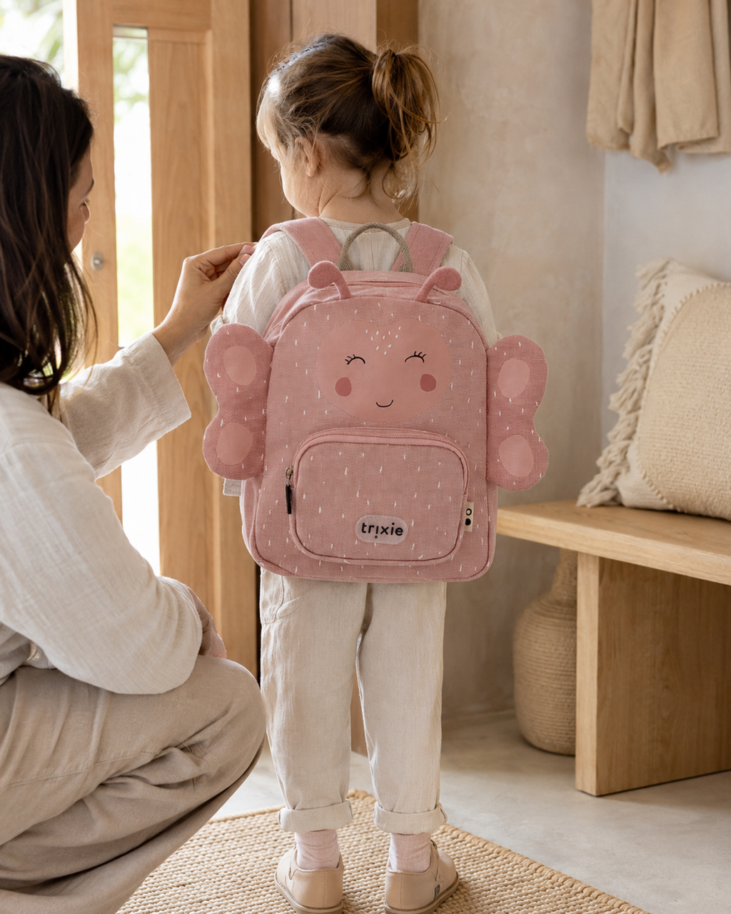 Mutter hilft Kind mit Kinderrucksack Mrs. Butterfly