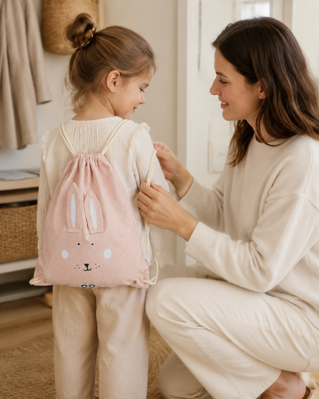 Mutter hilft Kind mit Turnbeutel Mrs. Rabbit