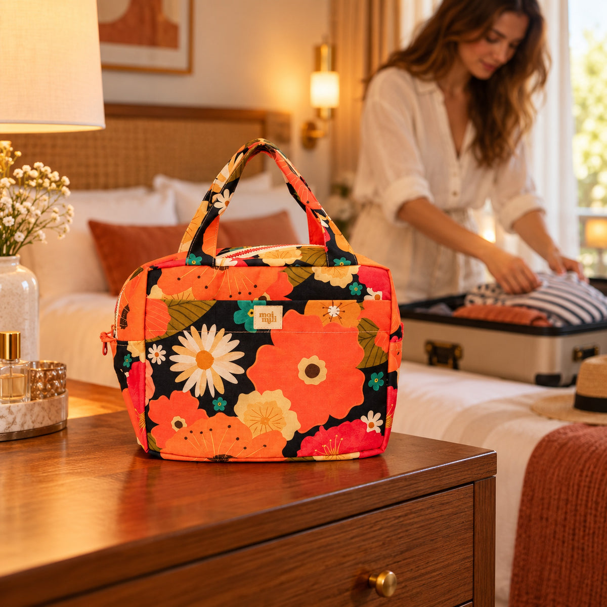 Große Kosmetiktasche Blumenpicknick mit orangefarbenem Blumenmuster im Hotelzimmer beim Packen einer Reise