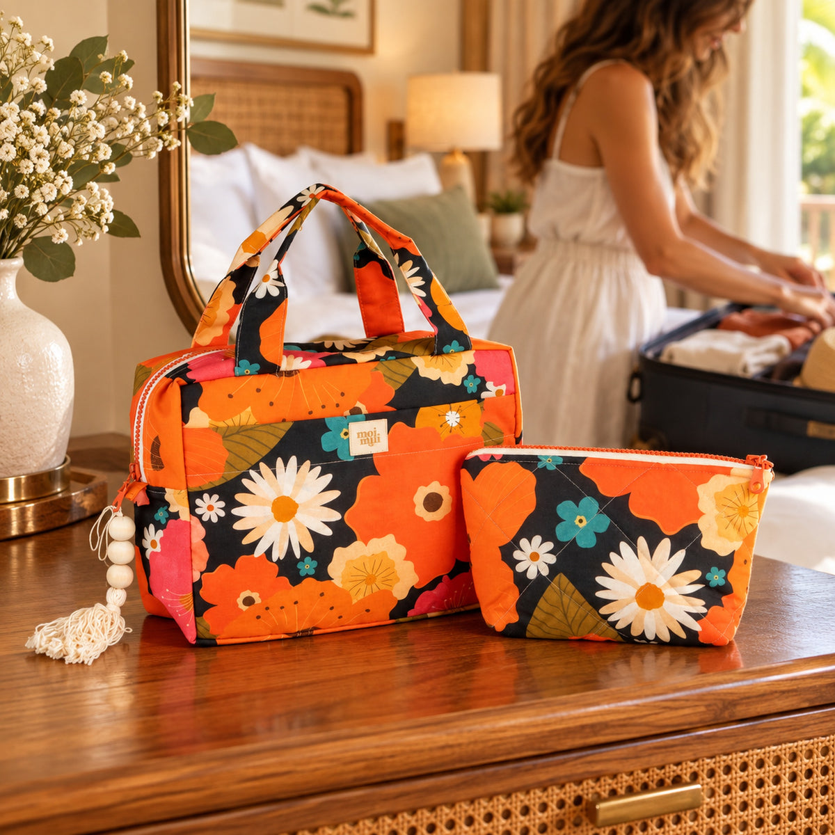 Zweiteiliges Kosmetiktaschen-Set Blumenpicknick mit orangefarbenen Blüten im Hotelzimmer, Frau packt einen Koffer