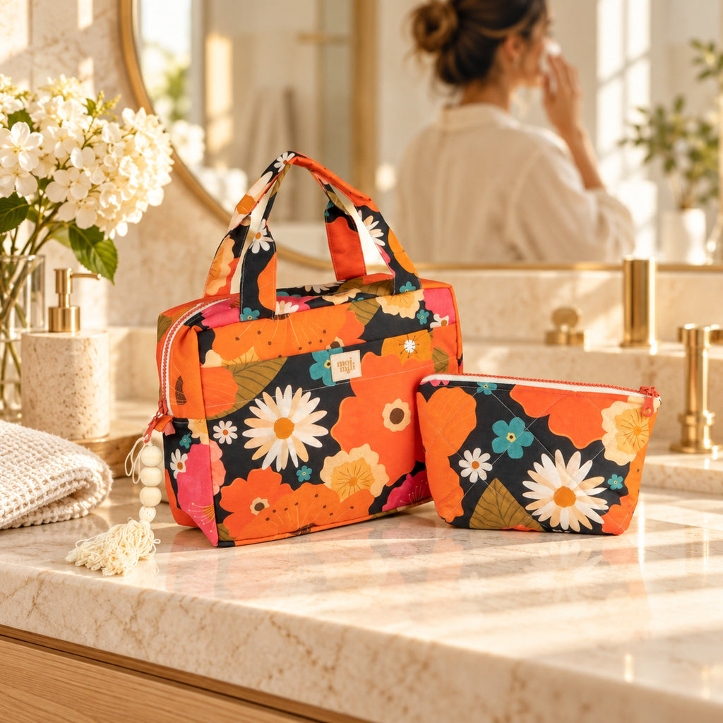 Zweiteiliges Kosmetiktaschen-Set Blumenpicknick mit orangefarbenen Blüten auf einem hellen Waschtisch, Frau am Spiegel