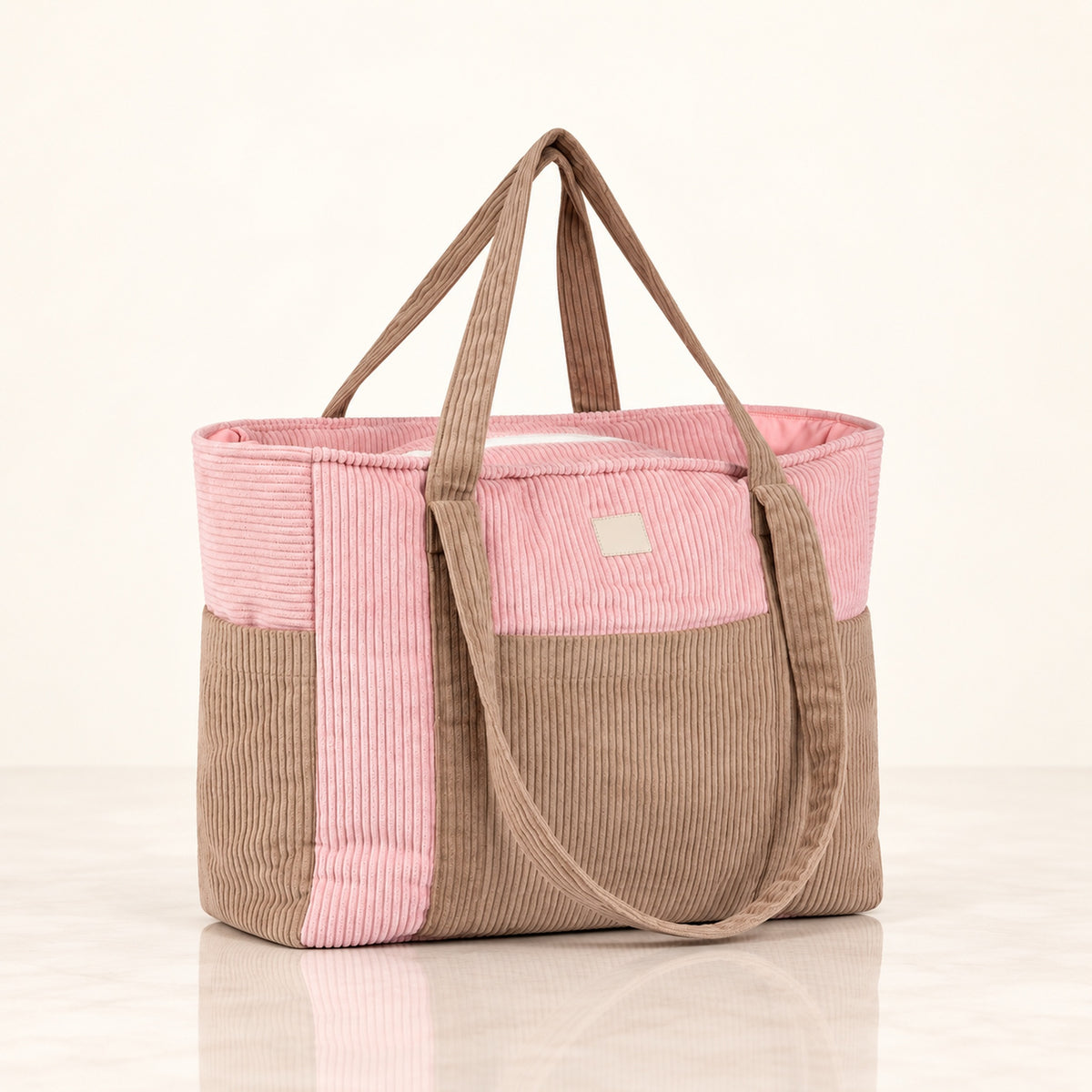 Mom Bag und Weekender Pink Coffee mit rosa und taupefarbenen Cordflächen auf hellem Spiegelboden